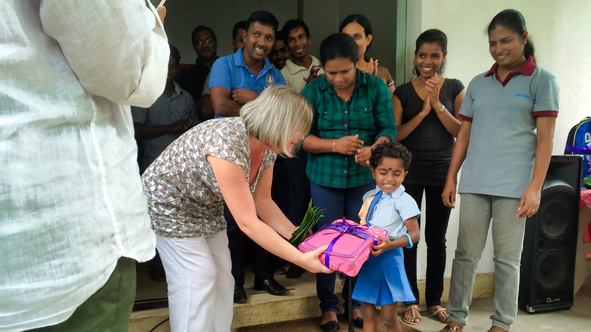 a lady handing a gift wrapped in pink paper to a small child
