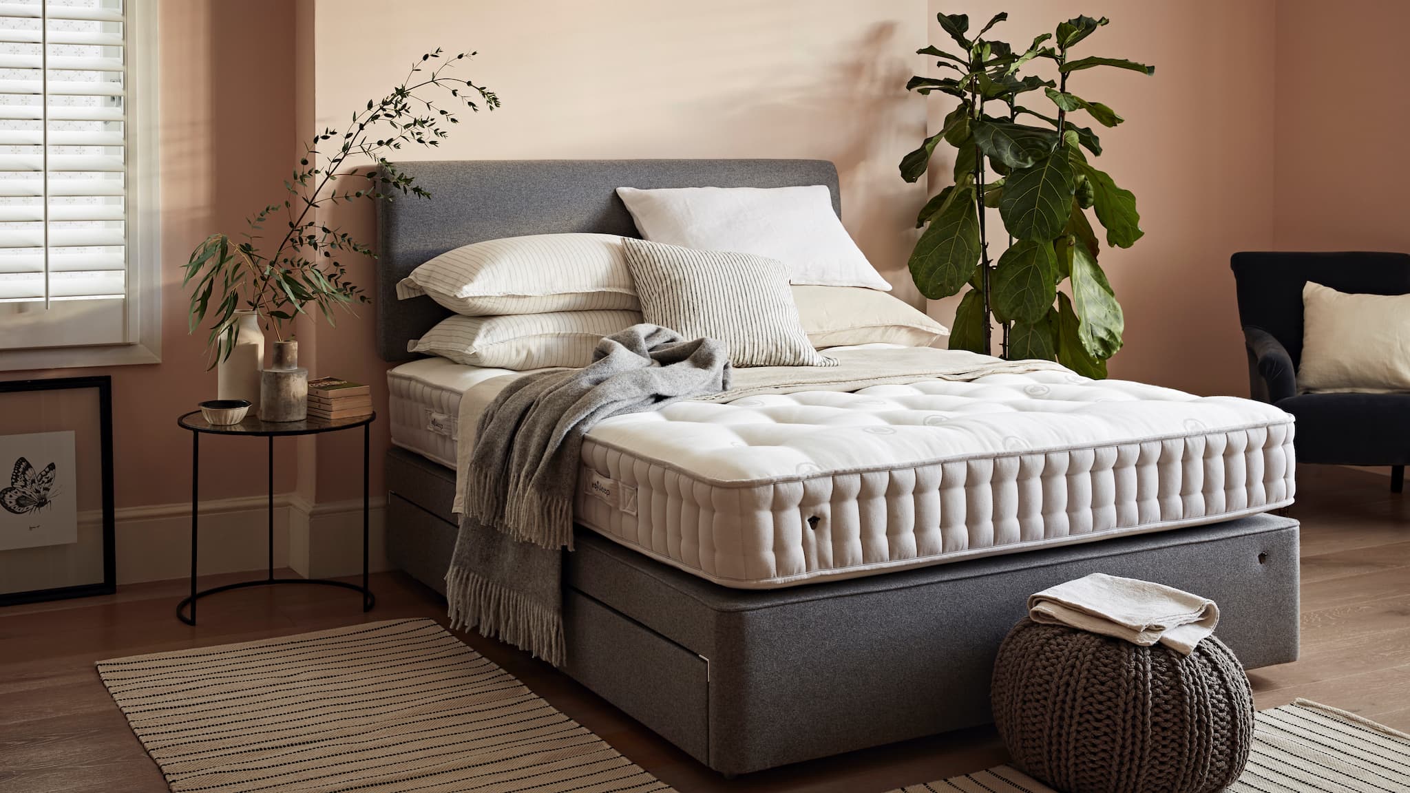 A herdysleep mattress in a light pink room with house plants