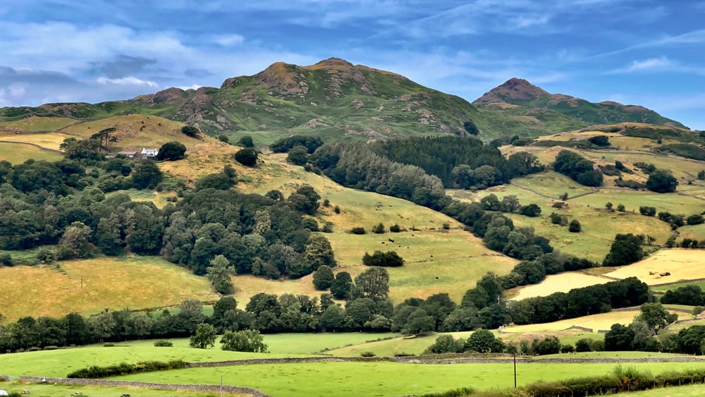 Lake District Landscape showing green mountains, farmland and blue sky